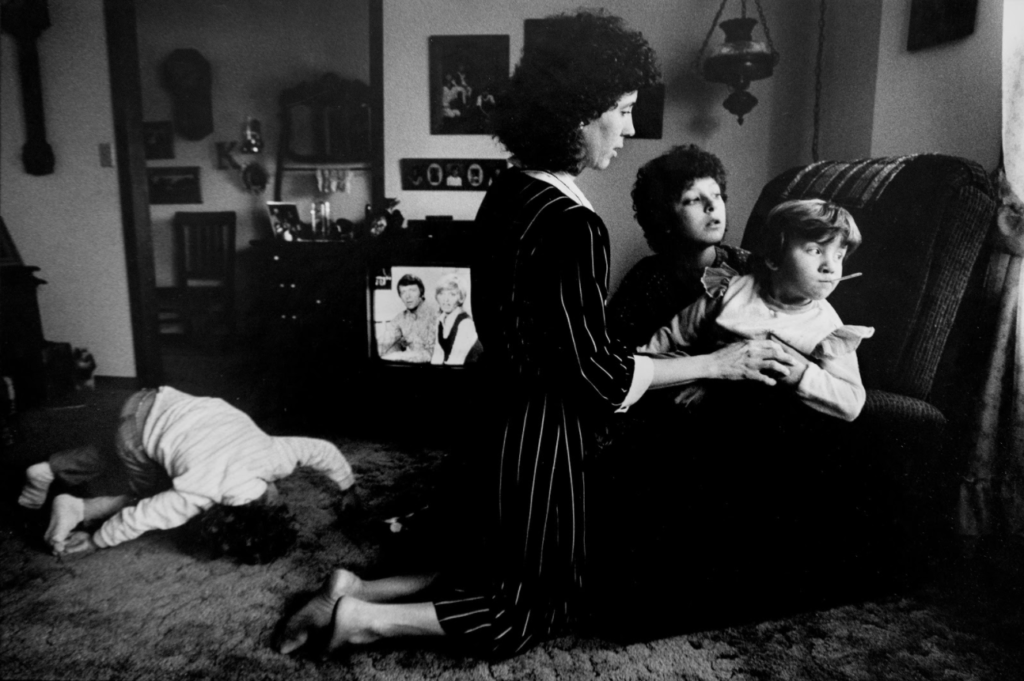 Carol Keusch checks the temperature of daughter Sandy, one of eight children adopted by Carol and husband David of Vincennes, Indiana. At left, restless daughter Amanda watches “The Brady Bunch” on TV. The family’s story covered six pages in the Feb. 8, 1986 edition of The Herald. Photo by Steve Mellon.