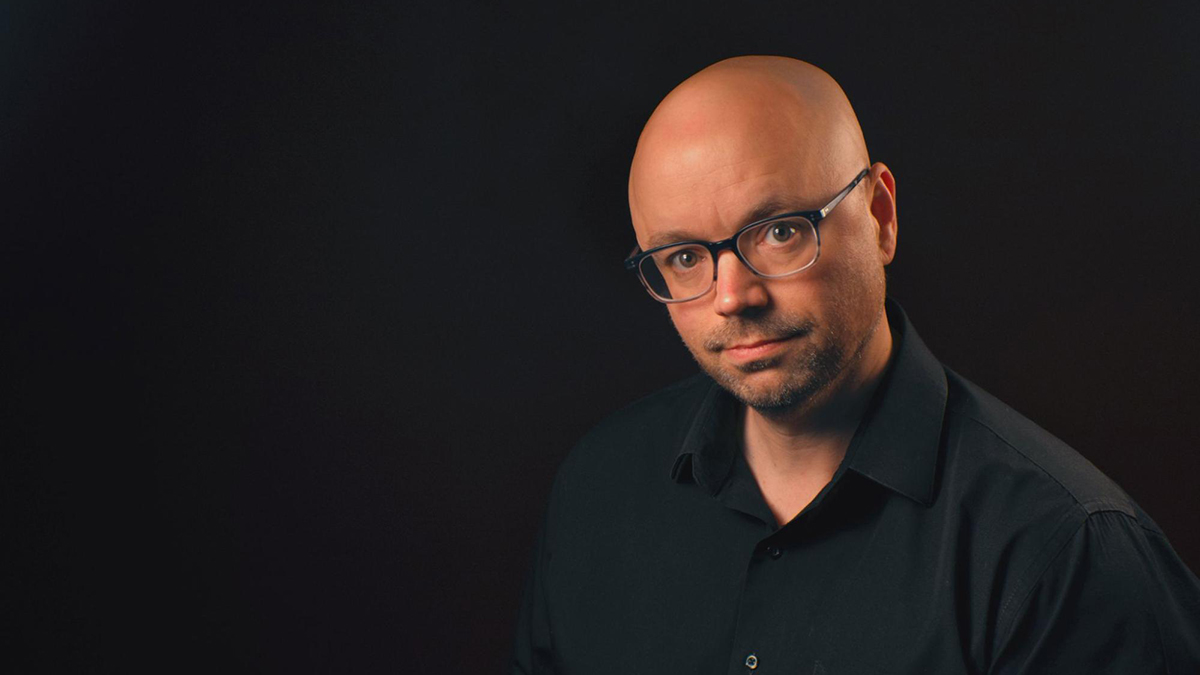 A professional headshot of TV anchor Stan Hiest set in front of a black background.