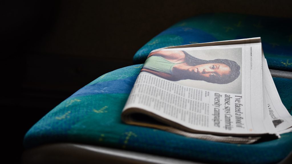 Newspaper on a bus seat featuring a photo of a young black woman. Photo: Julia Sabiniarz | Unsplash