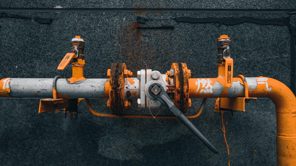 A steel pipeline with flaking orange paint. Photo: 夜 咔罗 | Unsplash