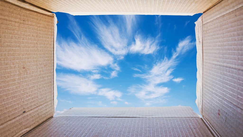 A cardboard box opens out to a blue sky with white wispy clouds.