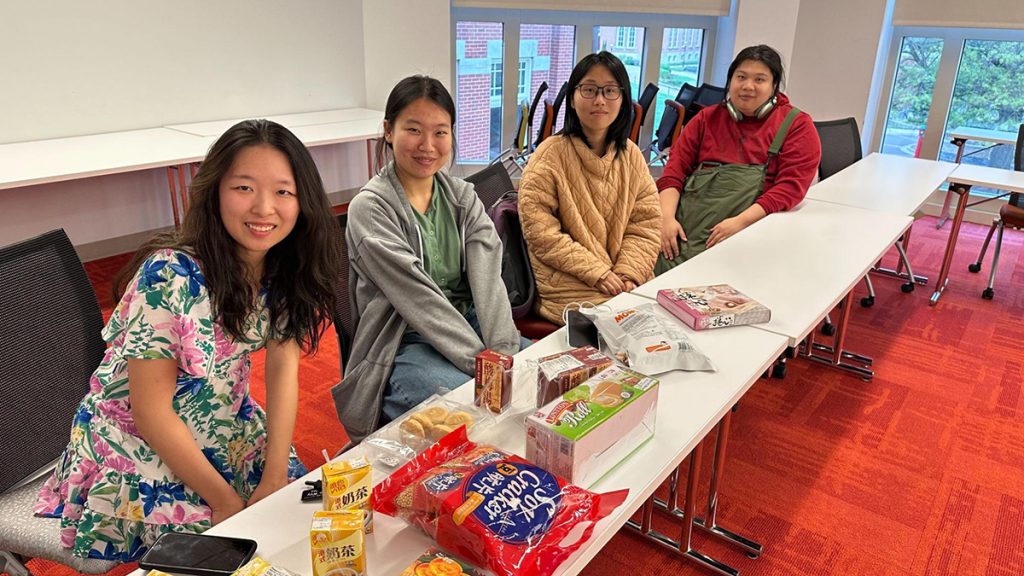 Four people sit at a table filled with snacks
