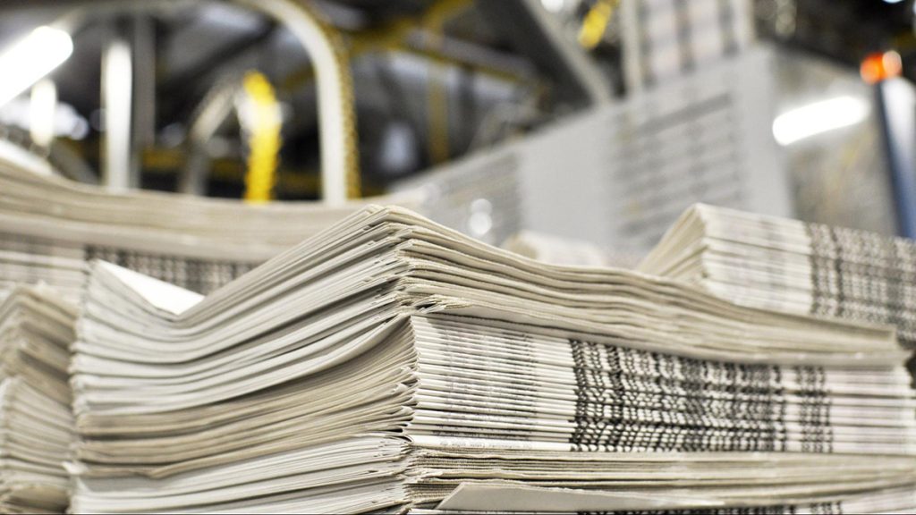 Stack of newspapers next to a printing press