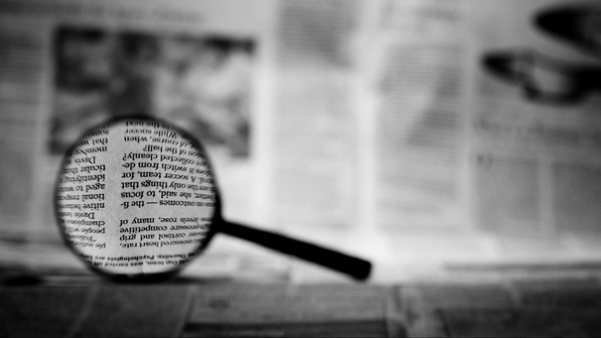 Magnifying glass sitting on a newspaper.