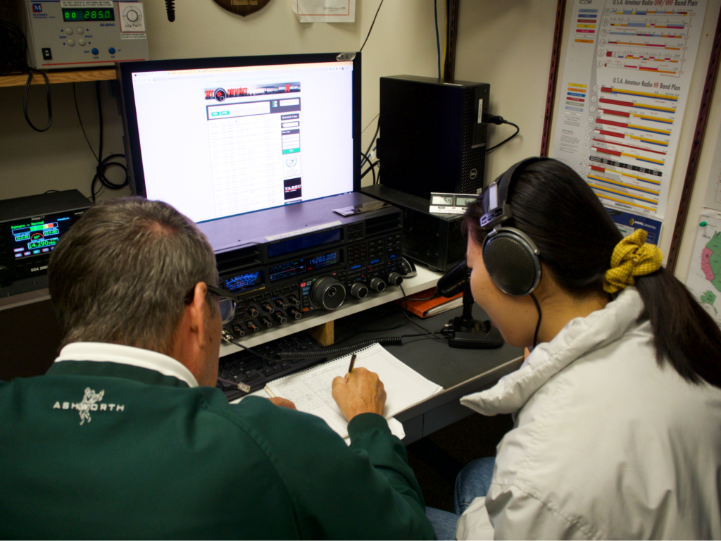 An Elmer helps a junior ham radio to make a worldwide contact through HF radios. Photo: María Arce
