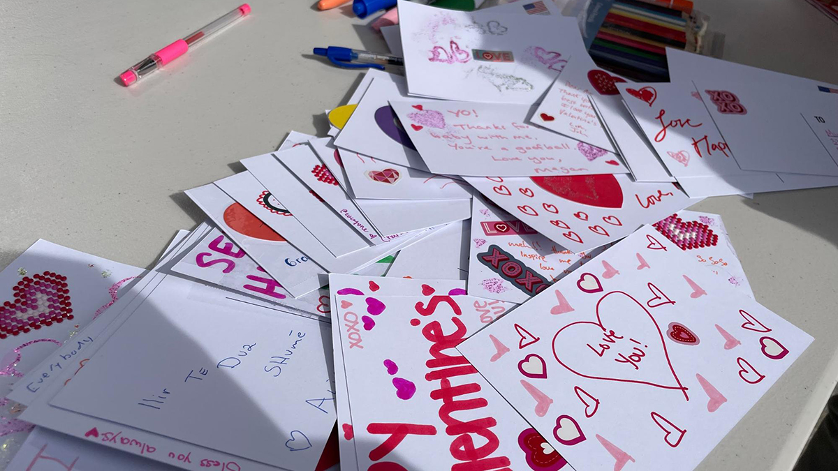 Handmade Valentine's Day cards with a variety of pens on a table outside.
