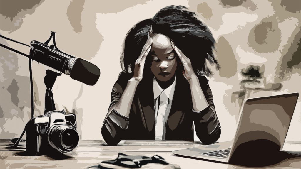 Journalist sits at desk suffering burnout