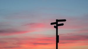 Sign post in silhouette against a sunset