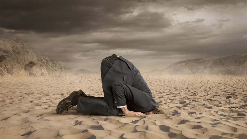 Man with head buried in sand