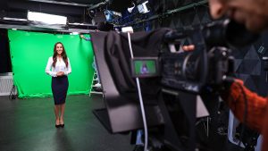 Woman doing a standup on camera in front of a green screen