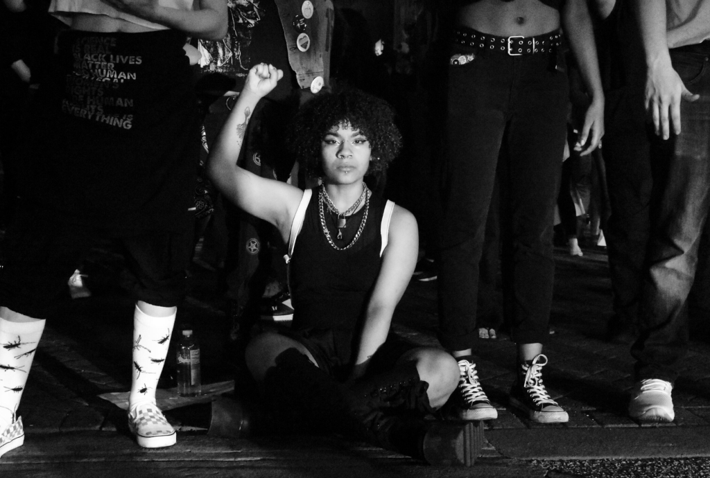 A Black woman sits in the middle of a busy intersection in downtown St. Louis, blocking oncoming traffic to protest against police brutality and the killing of George Floyd, on May 29, 2020. Photo: Vanessa Charlot