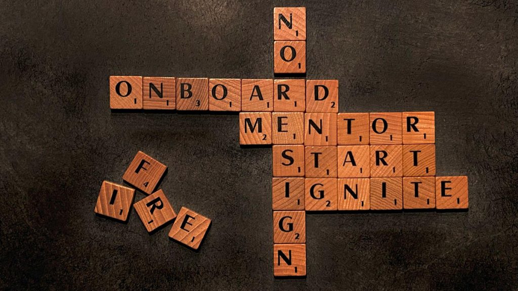 Scrabble tiles spelling out words: Onboard, mentor, start, ignite, no, resign, fire.