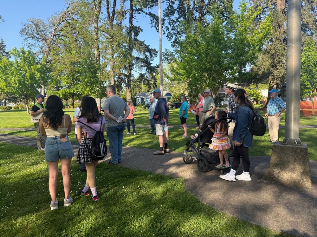 Participants at Newsberg’s first walking tour gather in a green area on May 1. 