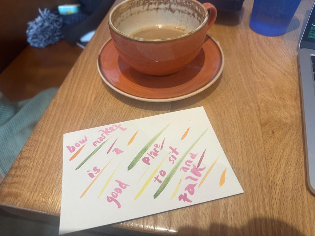 A half empty coffee cup with a napkin, on which is written bow market is a good place to sit and talk