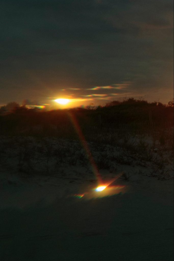 A sunrise or sunset reflected in a body of water.