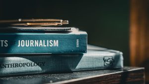 Journalism and anthropology textbooks with a pen and notebook on top