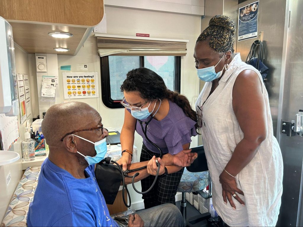 Members of MHM’s healthcare team take the blood pressure of a client in their mobile clinic.