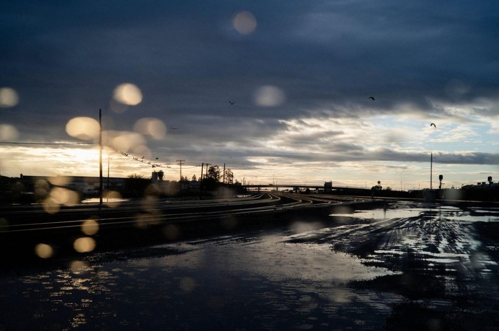 A rain-drenched highway with blue sky on the edge of storm clouds.