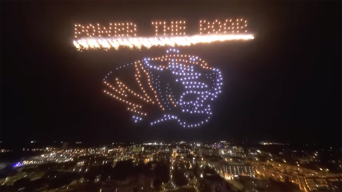 Drone light show above the University of Missouri campus featuring the university's tiger head logo with the words Power the Roar.