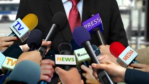 A plethora of microphones in front of a man in a tie