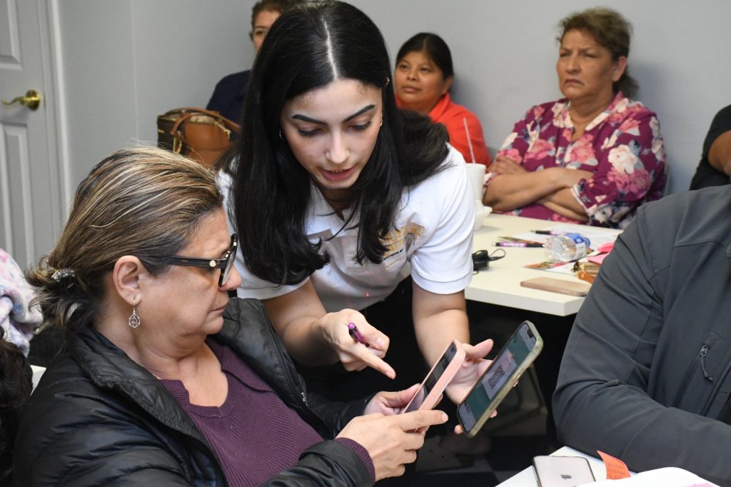 A young woman compares something on her mobile phone with an older woman on hers.