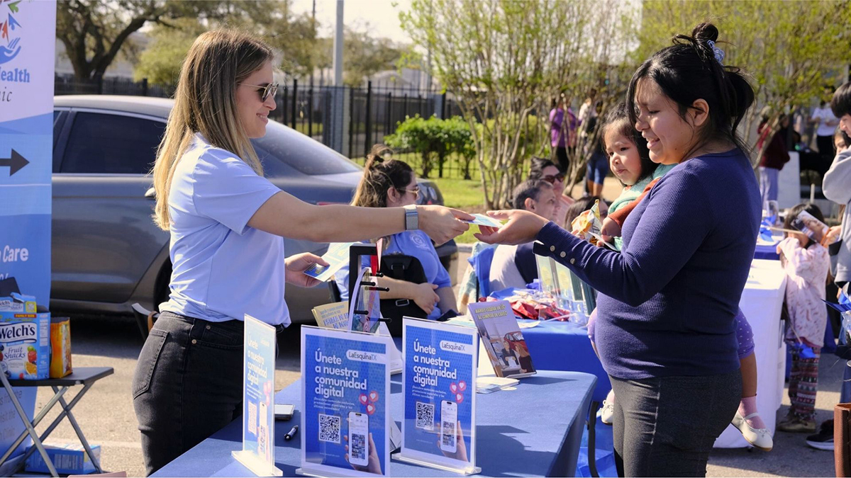 A woman hands something to another woman at a local community event.
