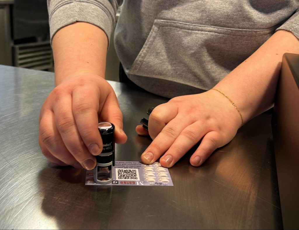 A Grind employee stamps a punch card for a customer at a local Grind location. 
