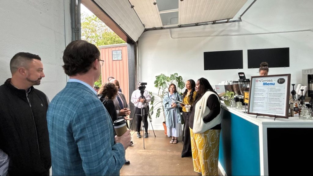 People standing around a coffee shop looking at a photographer