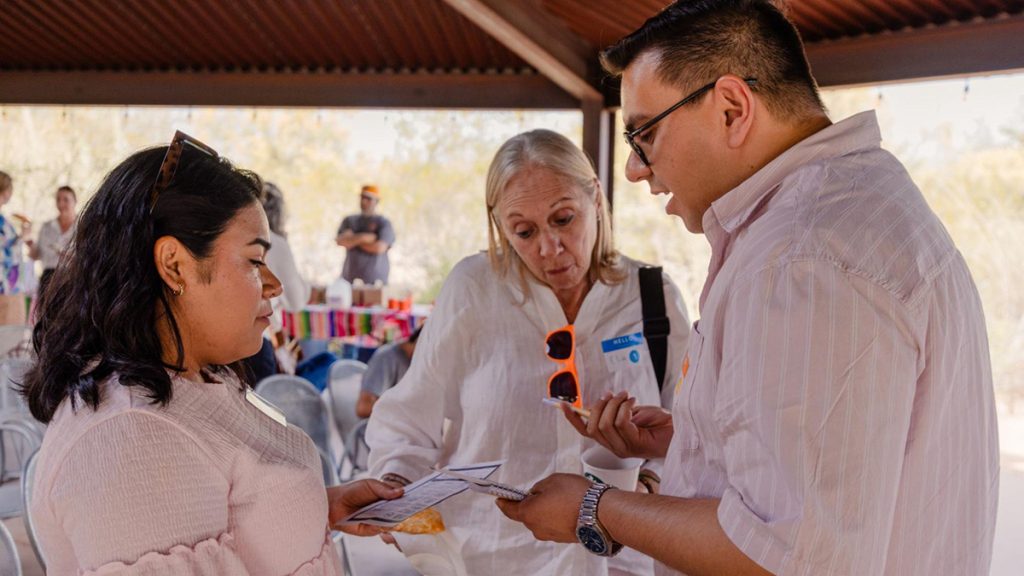 Three people looking at a document in a pavilion