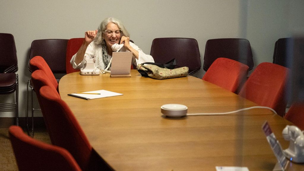 Woman sitting at a conference table talking on the telephone.