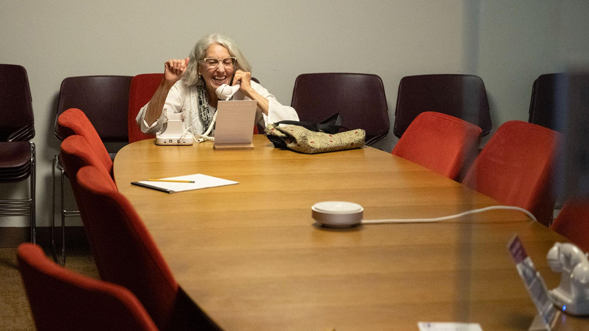 Woman sitting at a conference table talking on the telephone.