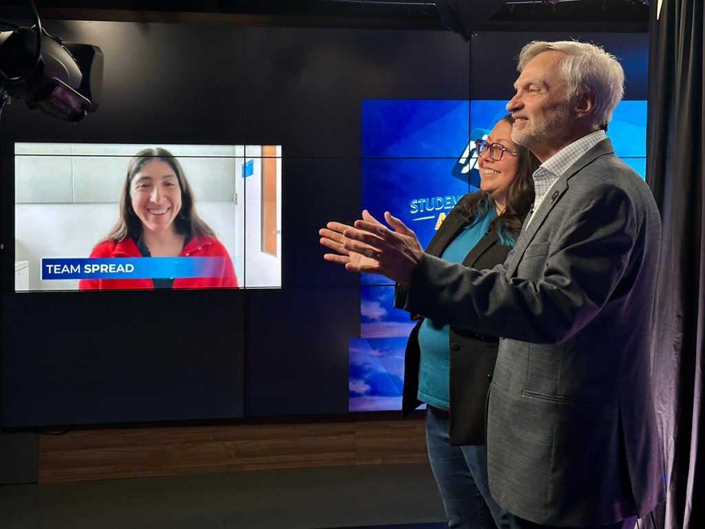 Randy Picht, executive director of the Reynolds Journalism Institute, congratulates Lauren Harris of Team Spread, which won the 2026 RJI Student Innovation Competition. Picht and Kat Duncan, center, RJI director of innovation, hosted the live announcement from the RJI TV studios at the Reynolds Journalism Institute. Harris is a student at Columbia University in New York City. Photo: Nate Brown